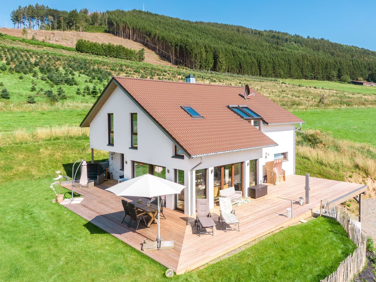 Modernes Fertighaus am Hang mit Satteldach und großer Terrasse