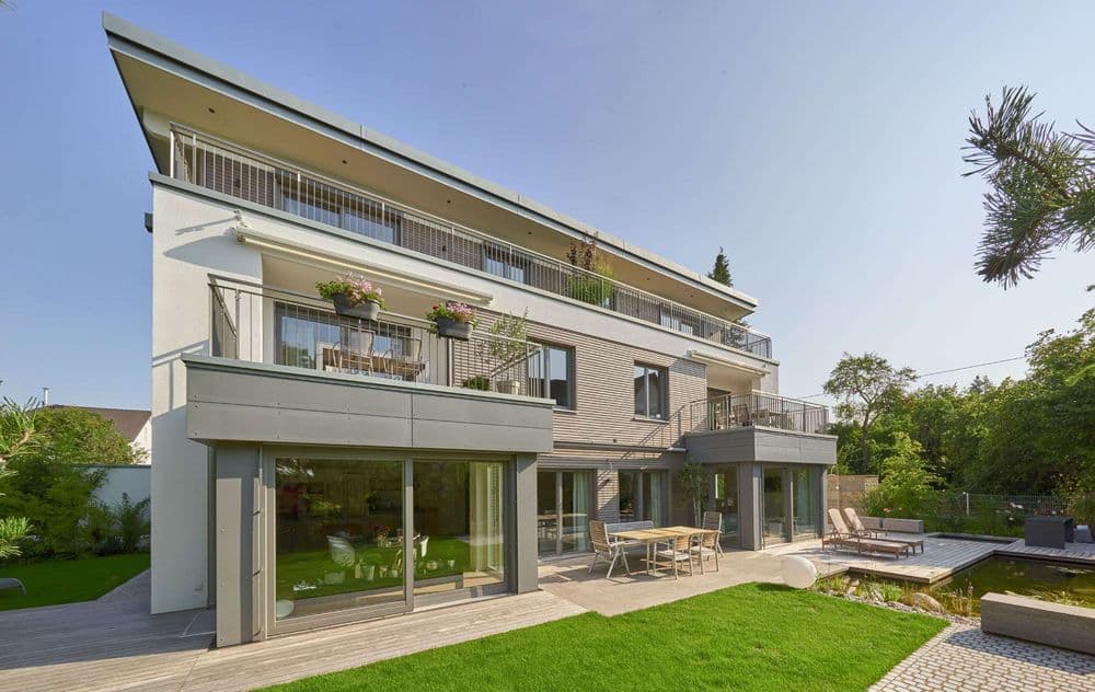 Holzhaus mit drei Wohneinheiten, mehreren Balkons und großer Terrasse