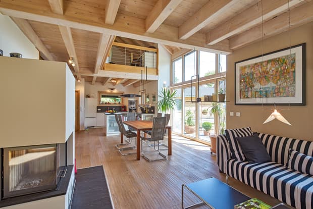 Der Wohn- und Essbereich des Holzhauses im Landhausstil, Lärchenfassade, große Glasfront, moderne Technik