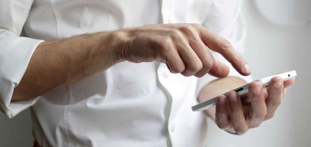 Mann in weißem Hemd bedient sein Smartphone
