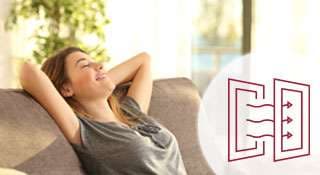 Frau sitzt entspannt auf einer Couch und genießt die Sonne