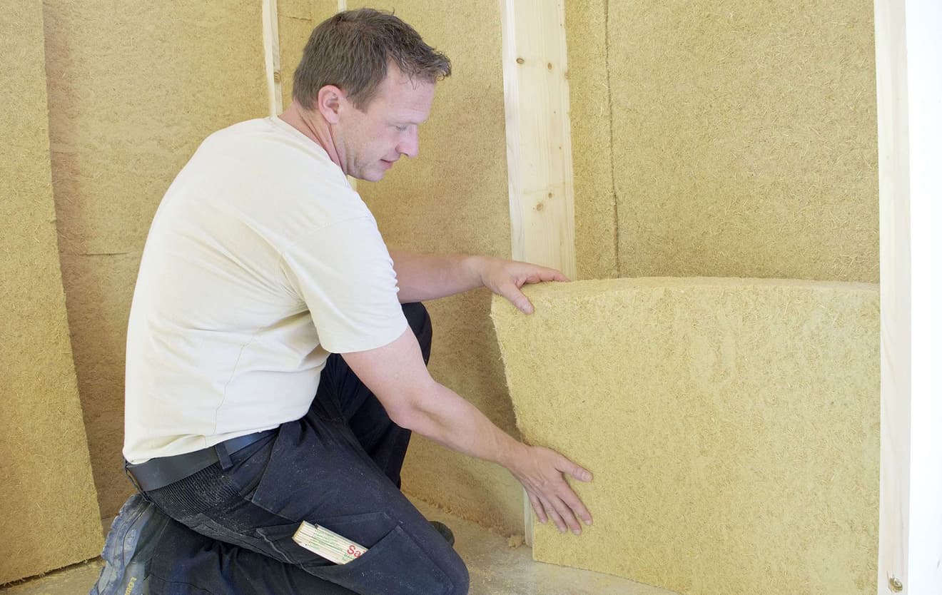 Handwerker baut Dämmung in die Wand eines Fertighauses