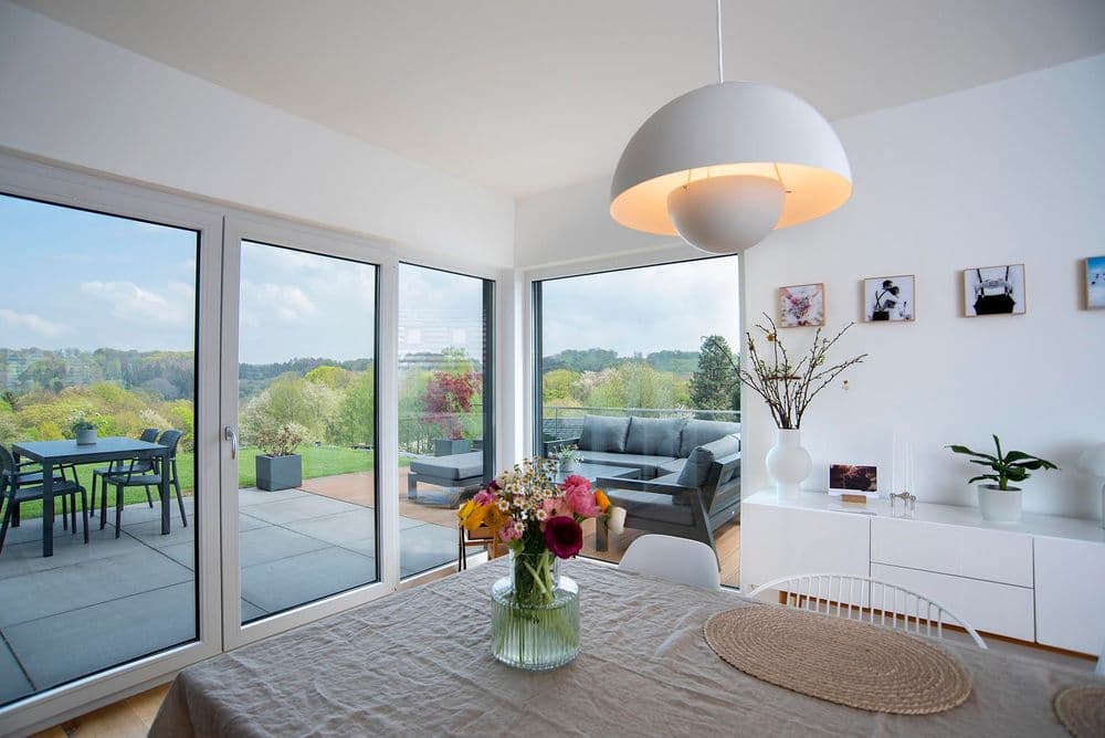 Helles Wohnzimmer mit bodentiefen Fenstern und Blick auf die Terrasse und den Garten