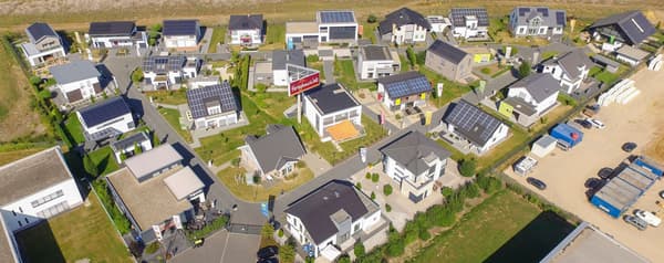 Luftaufnahme der FertighausWelt mit modernen Musterhäusern, Solardächern und grüner Umgebung, zeigt nachhaltige Architektur und energieeffizientes Wohnen.