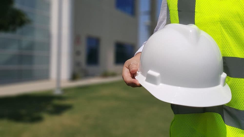 Mann mit Bauarbeiterhelm in der Hand
