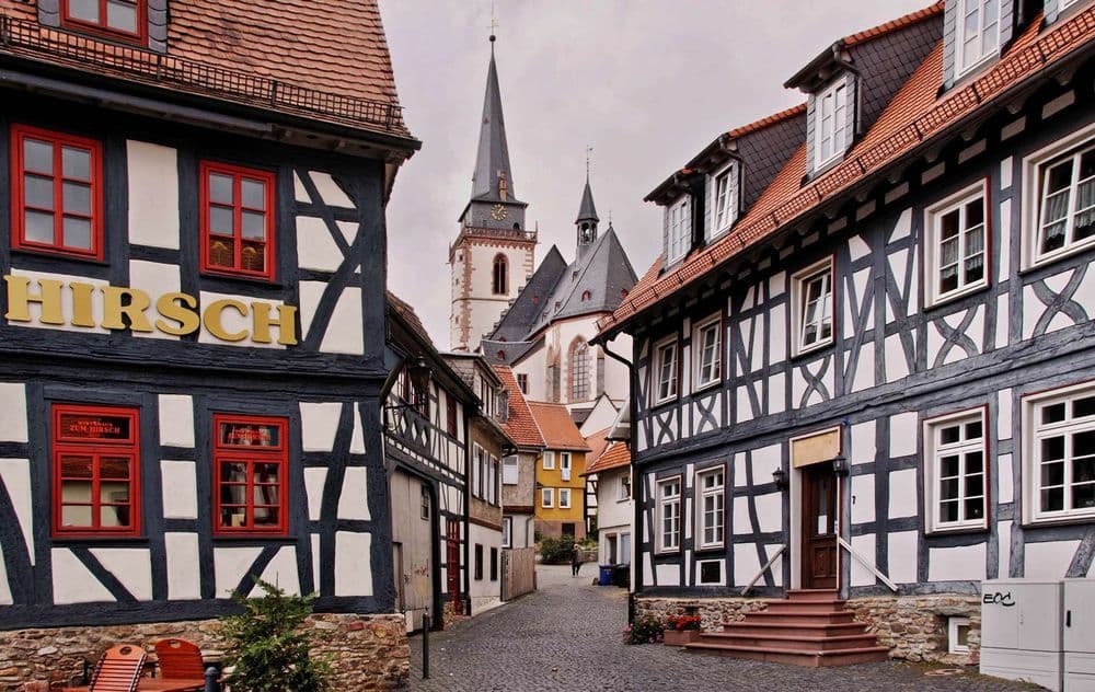 Historische Altstadt mit Fachwerkhäusern, Kopfsteinpflaster und Kirchturm im Hintergrund, zeigt traditionelles deutsches Stadtbild und Architektur.