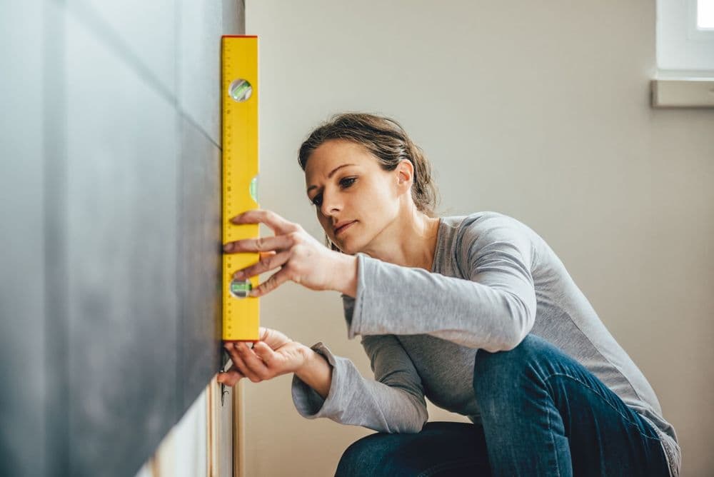 Frau misst die Neigung einer Wand mithilfe einer Wasserwaage
