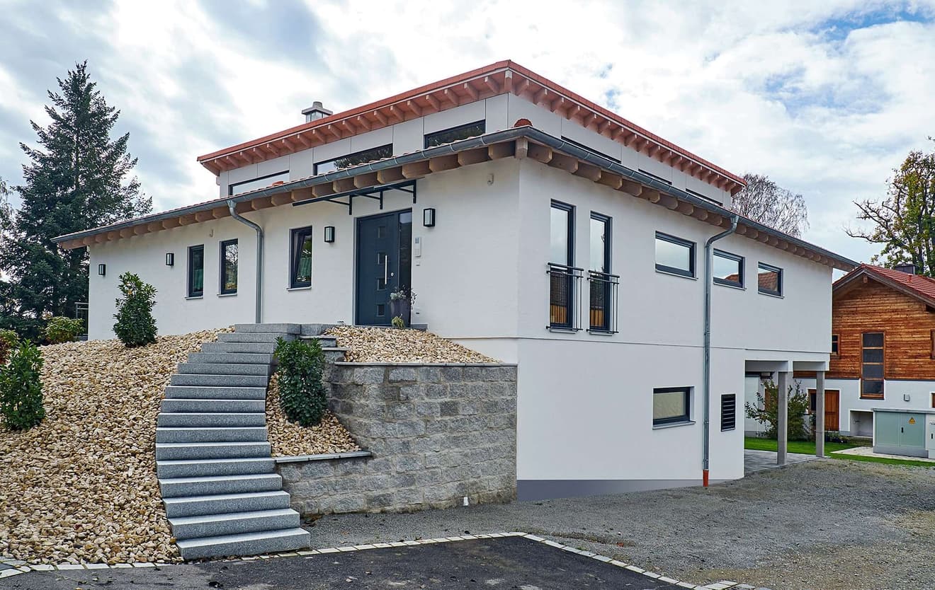 Moderner Bungalow aus Holz auf Hanggrundstück mit mineralischem Außenputz und Pultdach