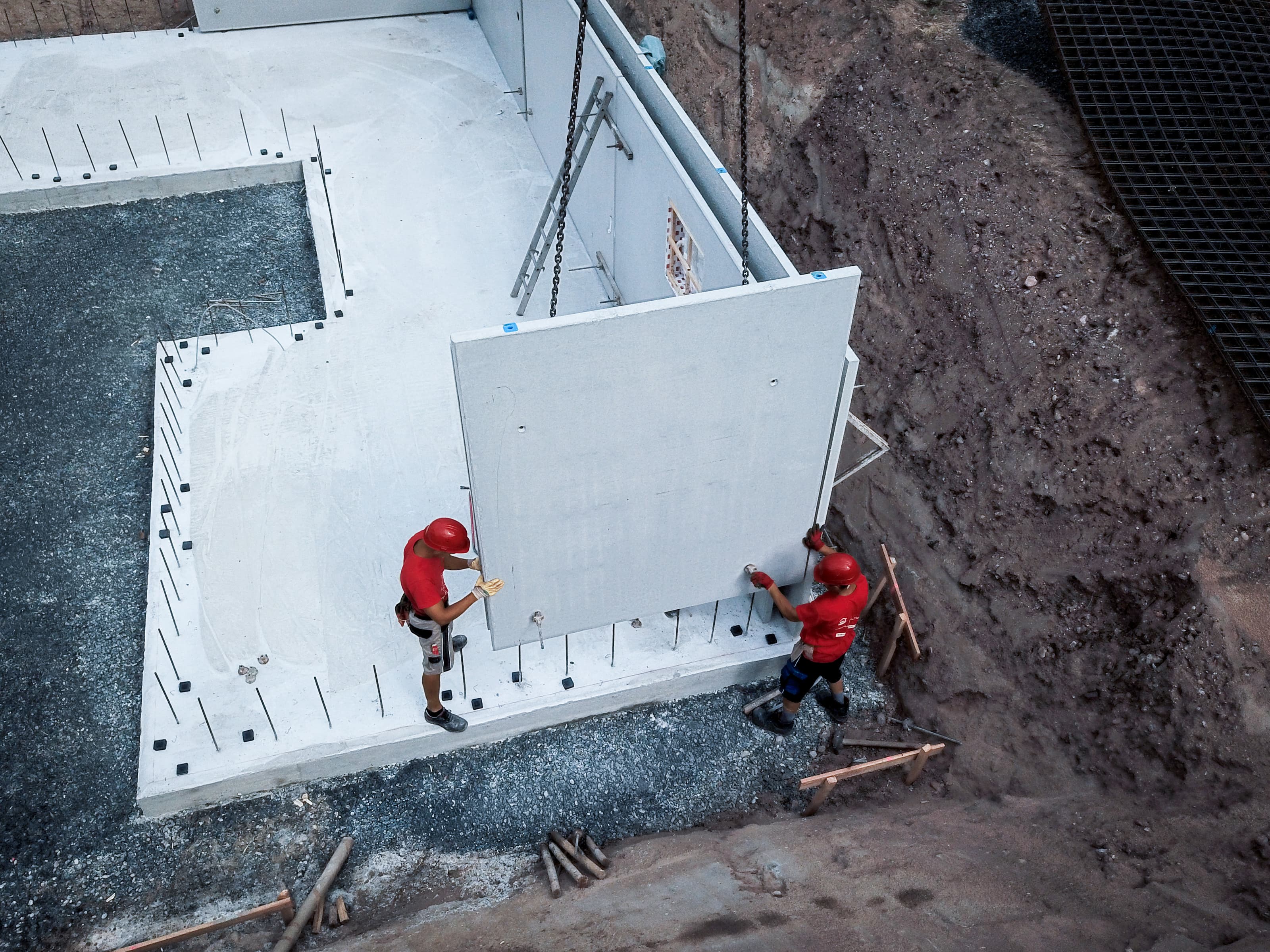 Fertighaus-Montage aus der Vogelperspektive: Bauarbeiter errichten Betonfertigteile mit Dämmsystem. Moderne Fertigbauweise, schneller Hausbau und professionelle Montage – effizient bauen.
