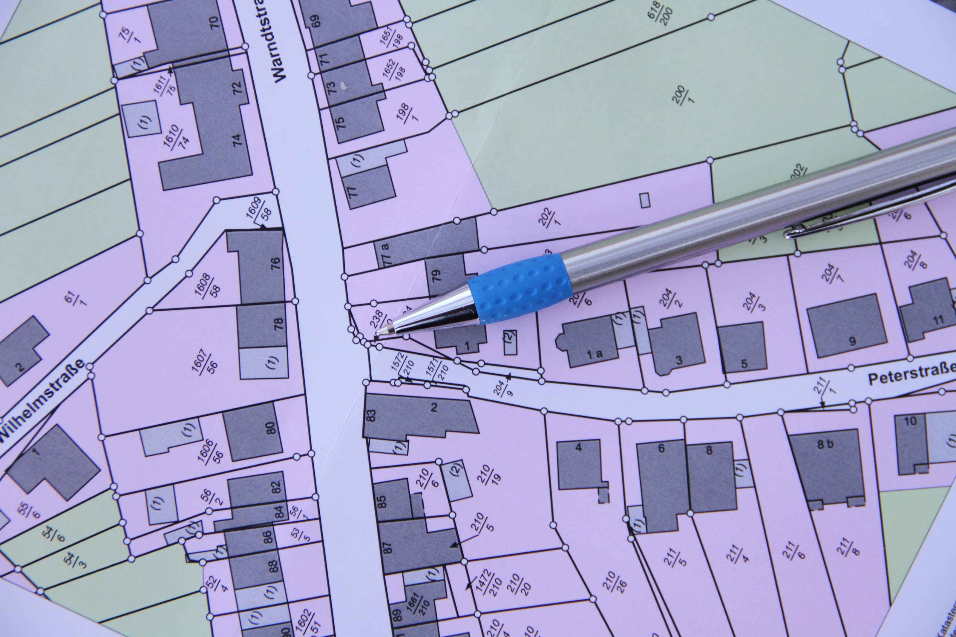 Stadtplan mit Grundstücksparzellen und Gebäuden, Straßenbeschriftung Wilhelmstraße und Petersstraße, Kugelschreiber zeigt darauf.