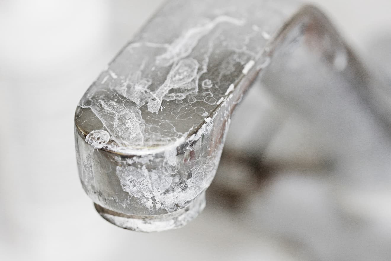 Eingefrorener Wasserhahn mit Eis ummantelt – typischer Frostschaden an Wasserleitungen durch Kälte und Kalkhaltiges Wasser