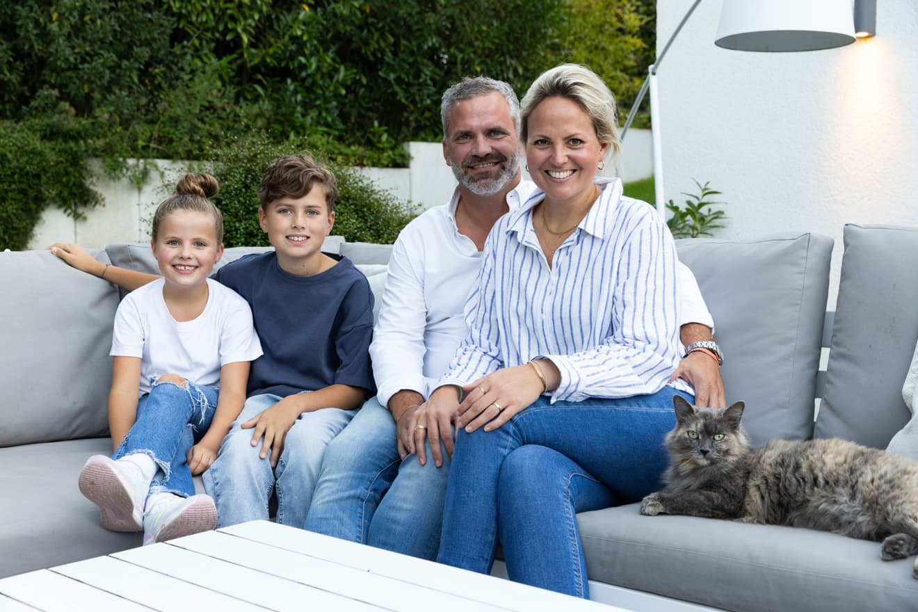 Glückliche Familie mit zwei Kindern und Katze auf dem Sofa im Garten