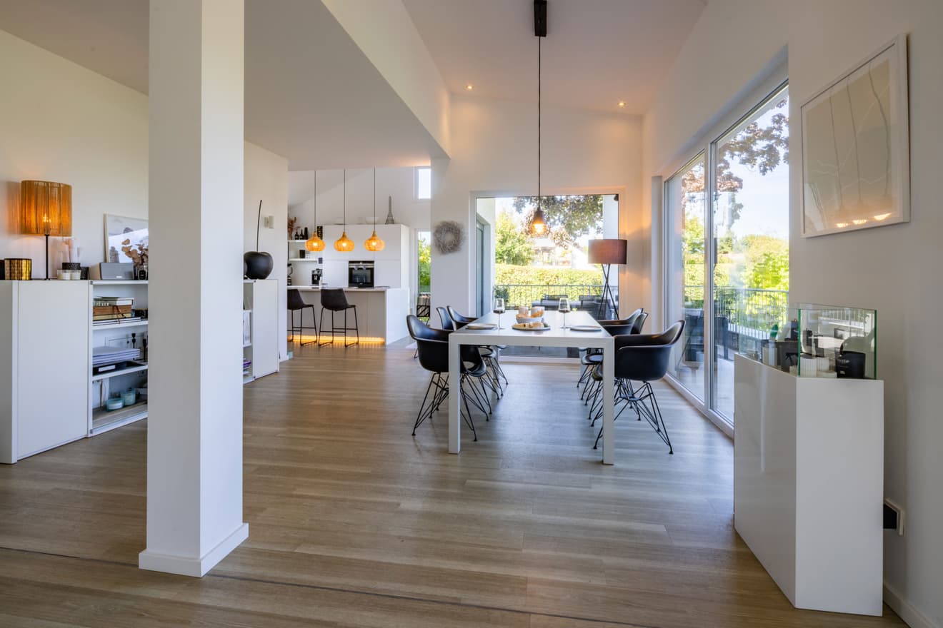 Heller, moderner Essbereich mit Holzboden, weißem Interieur und großer Fensterfront