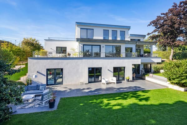Modernes, weißes Einfamilienhaus mit großer Terrasse, bodentiefen Fenstern und weitläufigem Garten