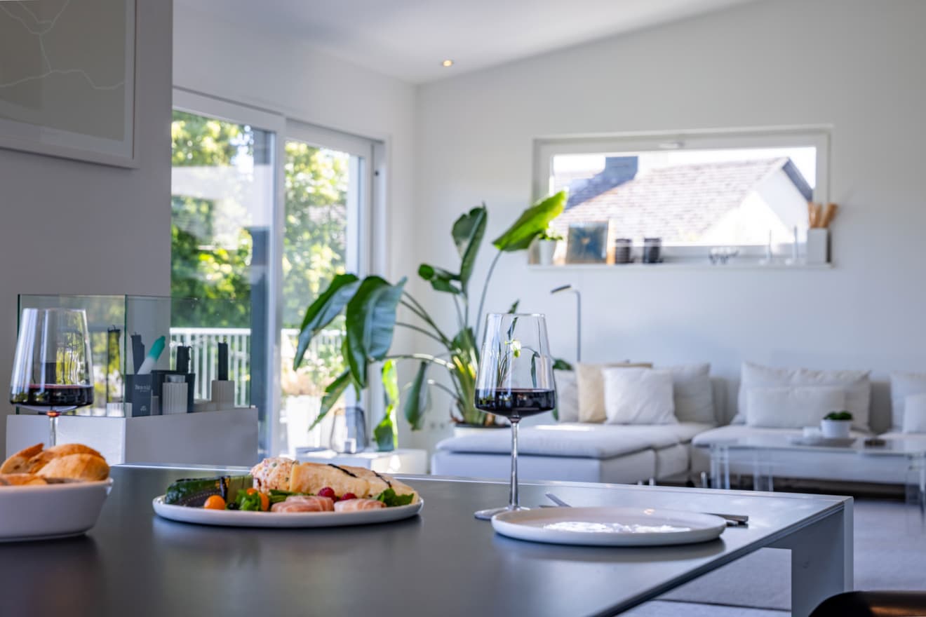 Stilvoll gedeckter Tisch mit Wein und Snacks in moderner, heller Wohnküche