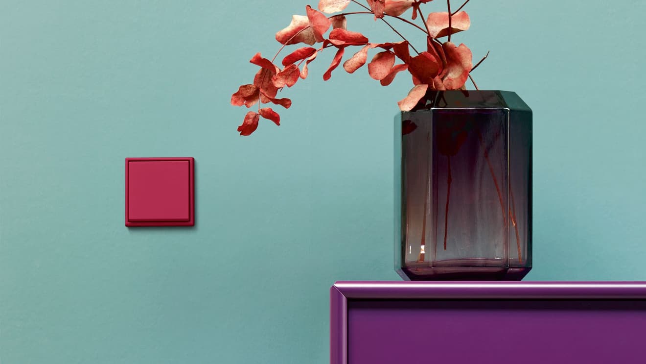 Roter Schalter von JUNG auf einer grünen Wand