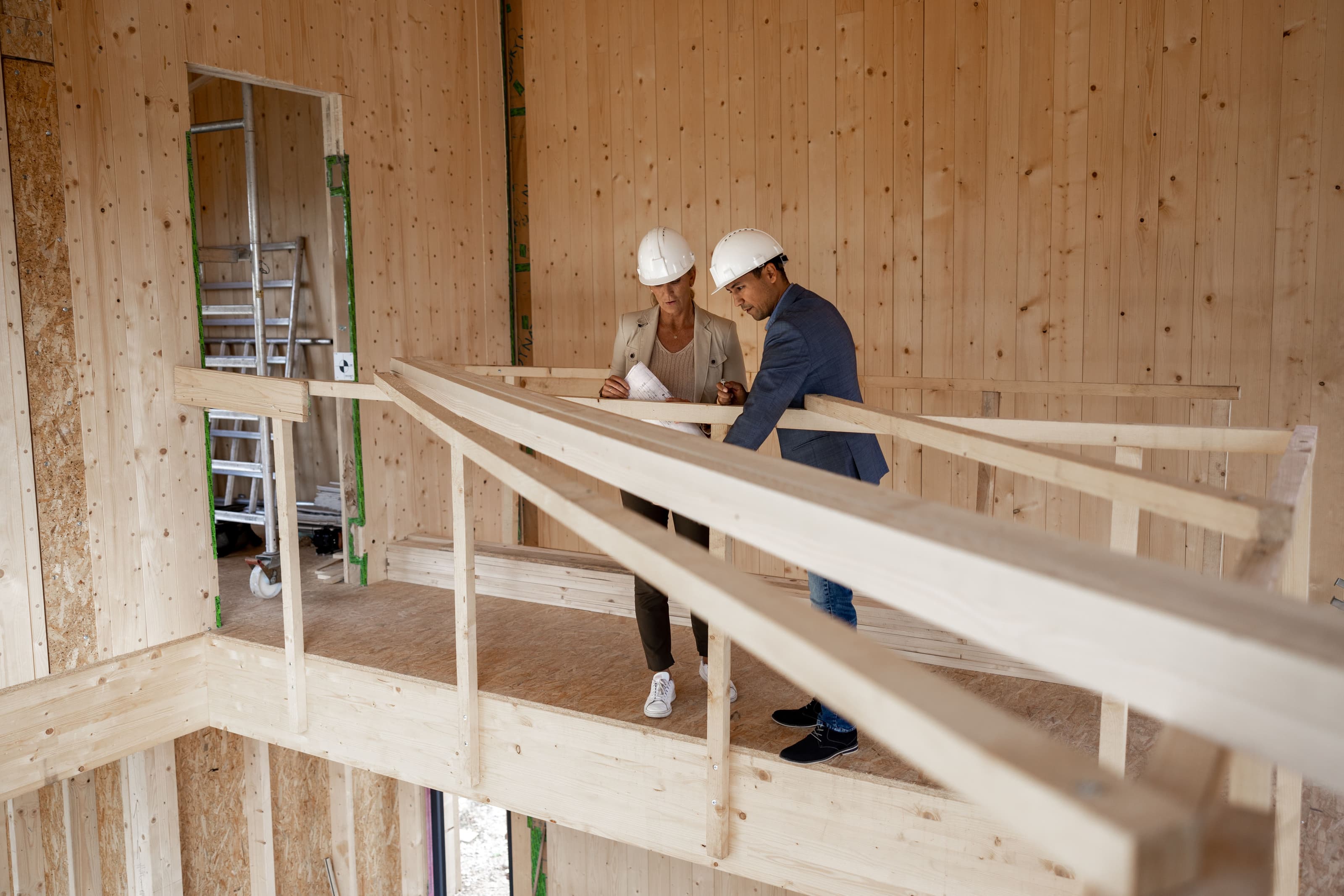 Zwei Handwerker stehen auf einer Galerie aus Bauholz