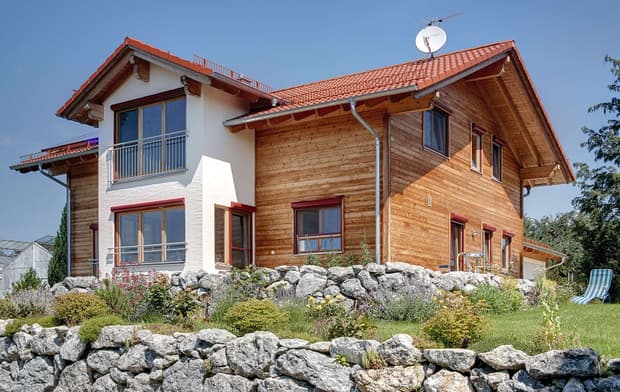 Großzügiges Holzhaus im Landhausstil mit Holzfassade und Erker mit mineralischem Außenputz