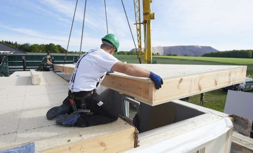 Handwerker bei dem Aufbau eines neuen Holz-Fertighauses