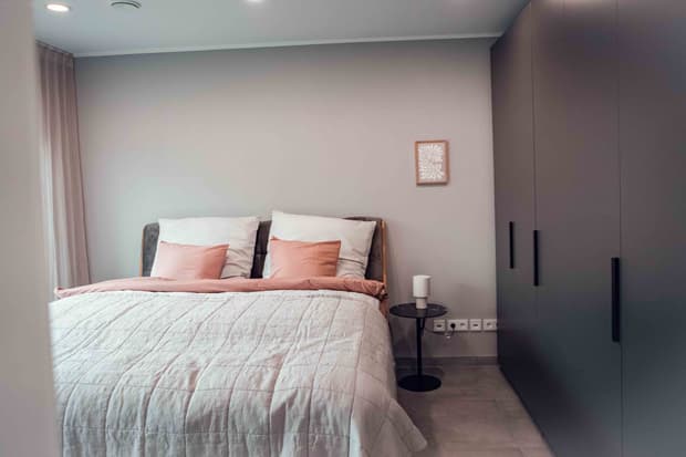 Innenaufnahme vom Streif Musterhaus in Fellbach. Ein modernes Schlafzimmer mit Doppelbett, gepolstertem Kopfteil, Nachttisch und Einbauschrank.
