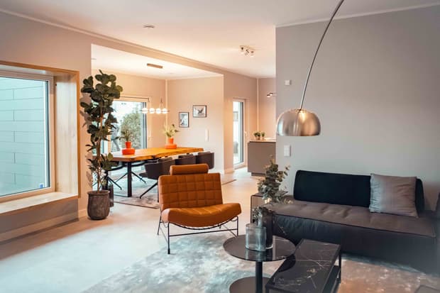 Die Innengestaltung vom Streif Musterhaus in Fellbach. Ein offener Wohn- und Essbereich mit Sofa, Sessel, Esstisch und großen Fensterflächen.