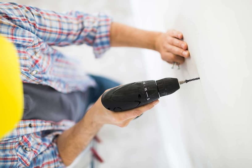 Handwerker befestigt Schraube in einer Fertighauswand