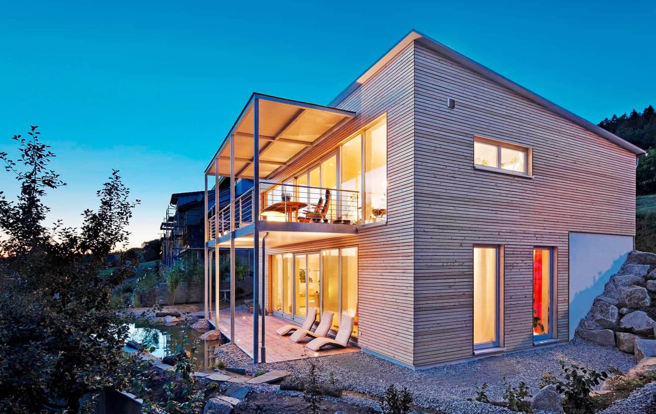Modernes Fertighaus mit Holzverschalung, überdachter Terrasse und Balkon