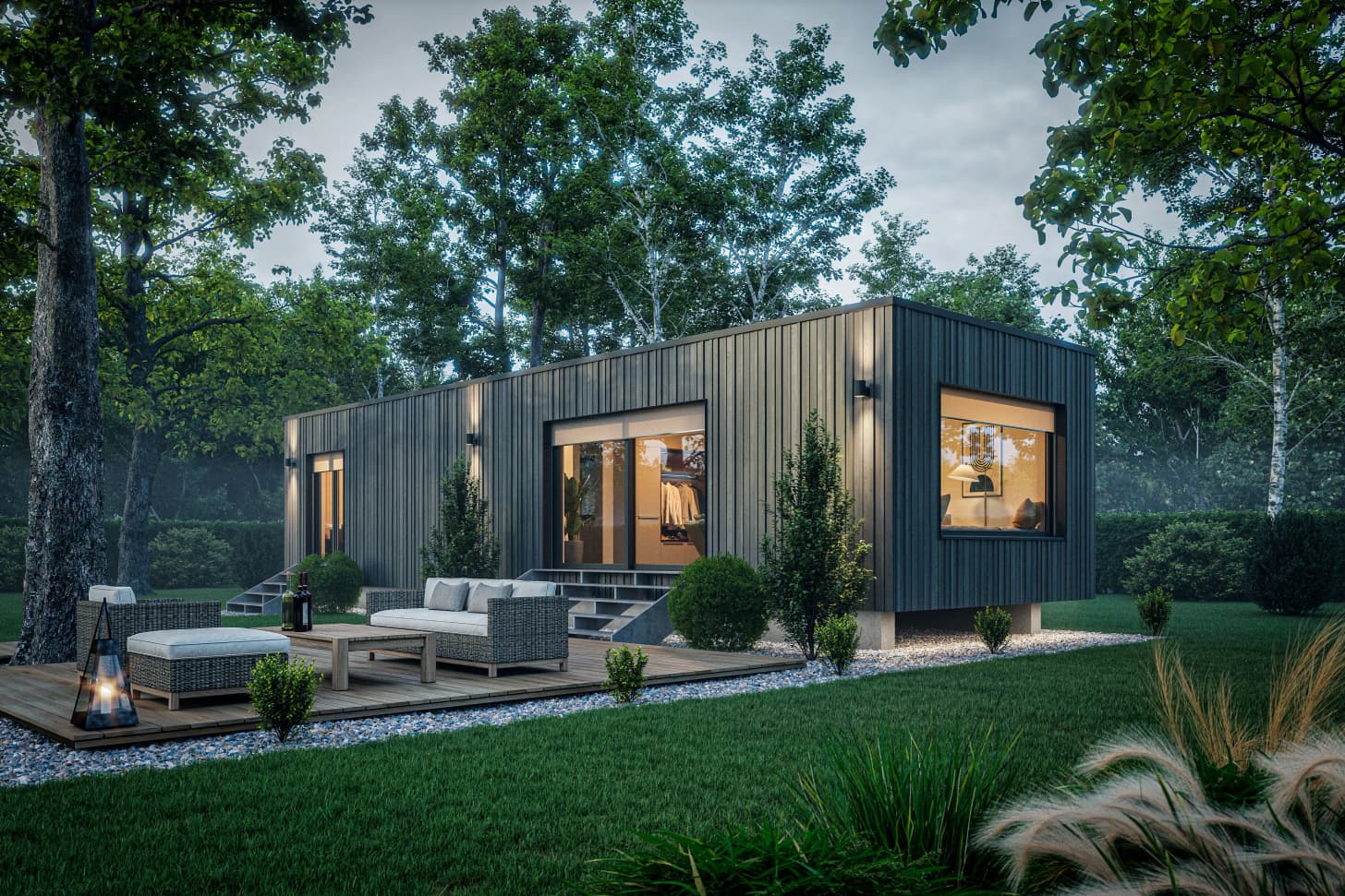 Modernes Fertighaus mit dunkler Holzvertäfelung und großer Terrasse mit Gartenmöbeln umgeben von grünem Wald