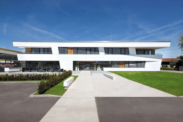 Modernes Bürogebäude in Seebruck mit markanter Architektur. Gewerbebau mit weißer Fassade, Holzelementen und großzügiger Außenanlage am Chiemsee.