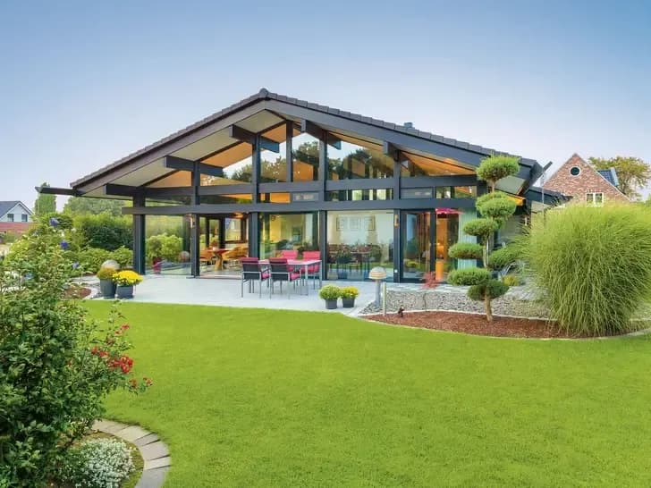 Moderner Bungalow mit großer Glasfassade, offenem Wohnbereich und gepflegtem Garten – stilvolles Hausdesign mit viel Licht und Weitblick.