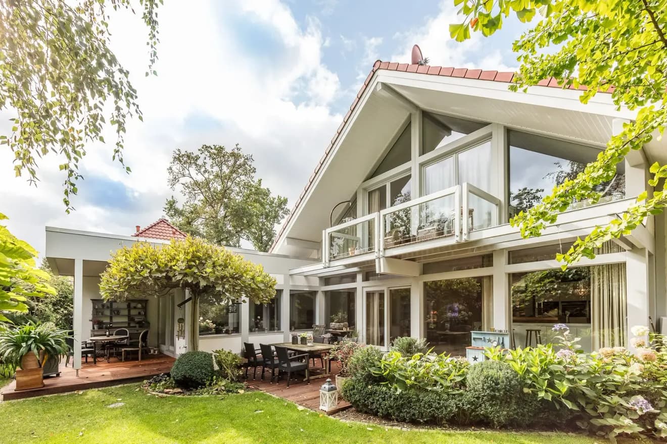 Moderner Anbau mit Glasfassade, Balkon und gepflegtem Garten – lichtdurchflutetes Wohnhaus mit stilvoller Architektur und offenem Wohngefühl.