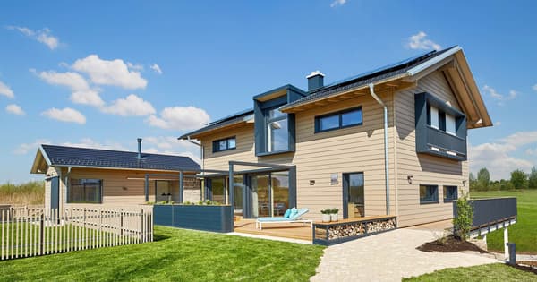 Modernes zweigeschossiges Holzhaus mit Flachdach-Erker, großer Terrasse, Glasfronten und angrenzendem Nebengebäude mit Solardach
