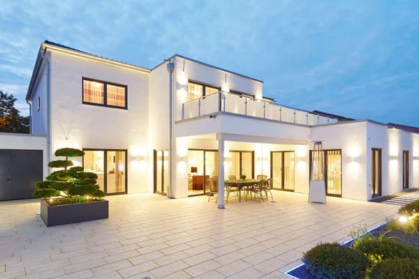 Zweigeschossiges modernes Einfamilienhaus mit weißer Putzfassade, Flachdach-Elementen und großen bodentiefen Fenstern.
