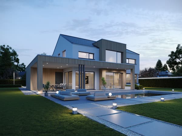 Modernes Haus mit beleuchtetem Pool und Terrasse in der Abenddämmerung.