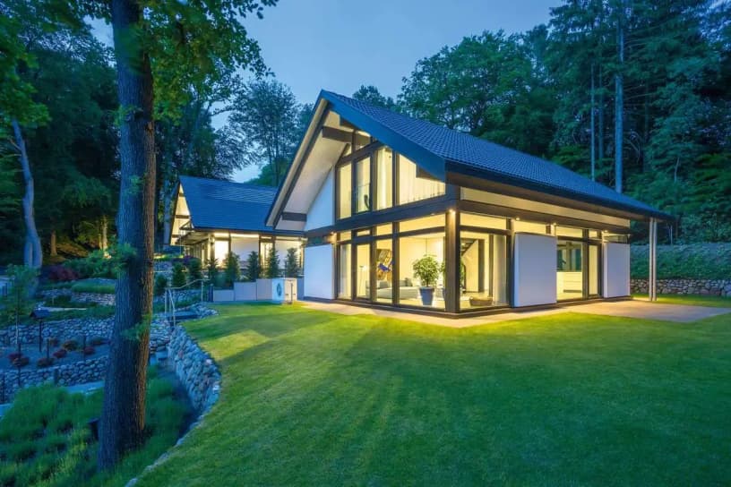 Wärmepumpe Fertighaus: Modernes Einfamilienhaus in Skelettbauweise mit Abendbeleuchtung